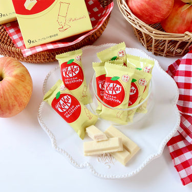 On a table, netx to some apples, a pack of KitKat